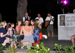 Frauen am Tisch beim Wein trinken mit Band im Hintergrund